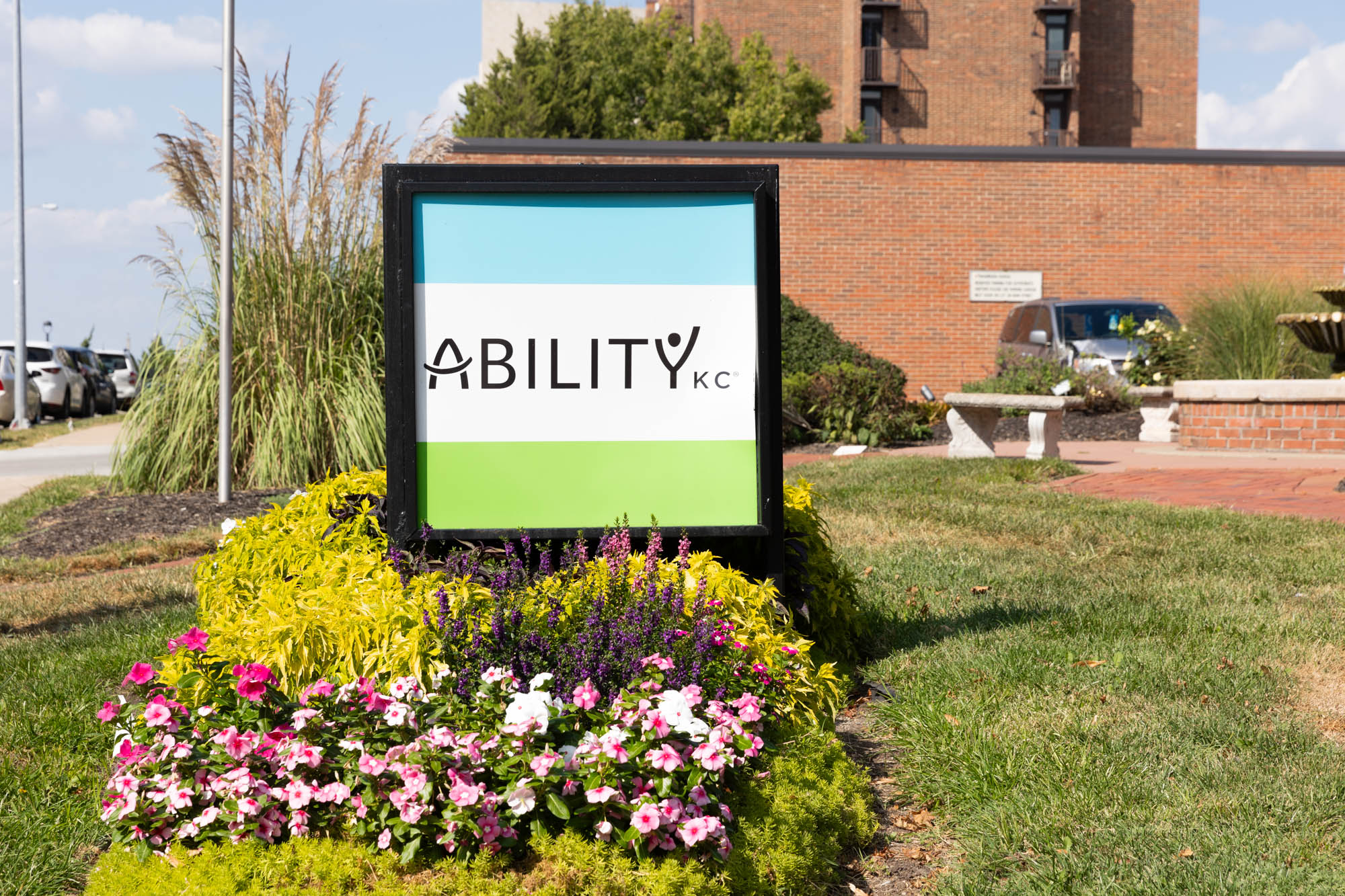 Outdoor Ability KC sign on Baltimore Avenue with flowers behind