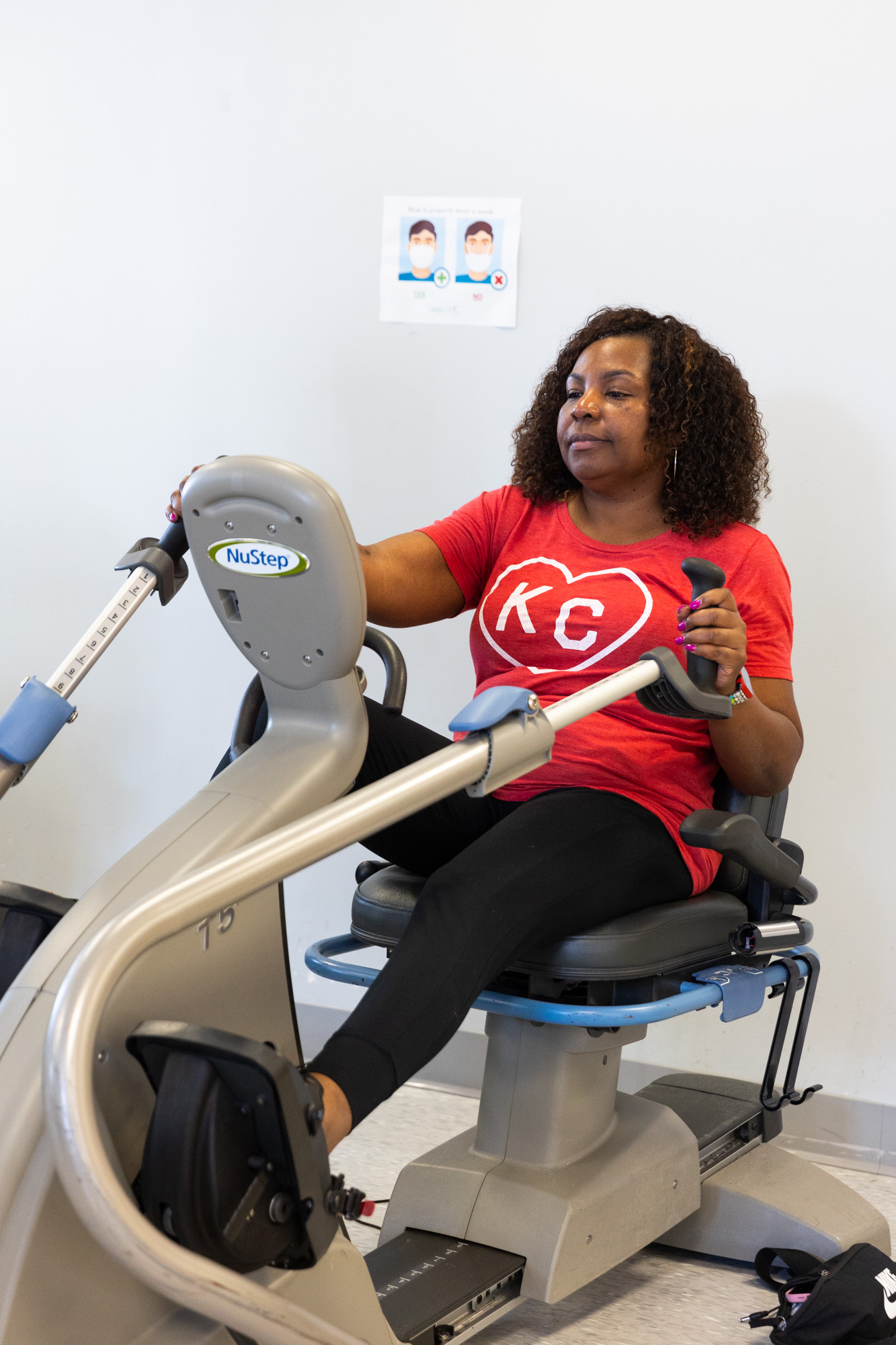 Patient in red KC shirt using gym equipment