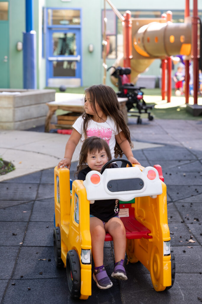 two children in play car on playground