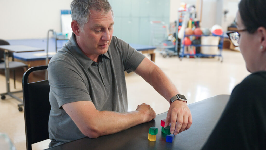 Chris working with colorful blocks, equipment in background