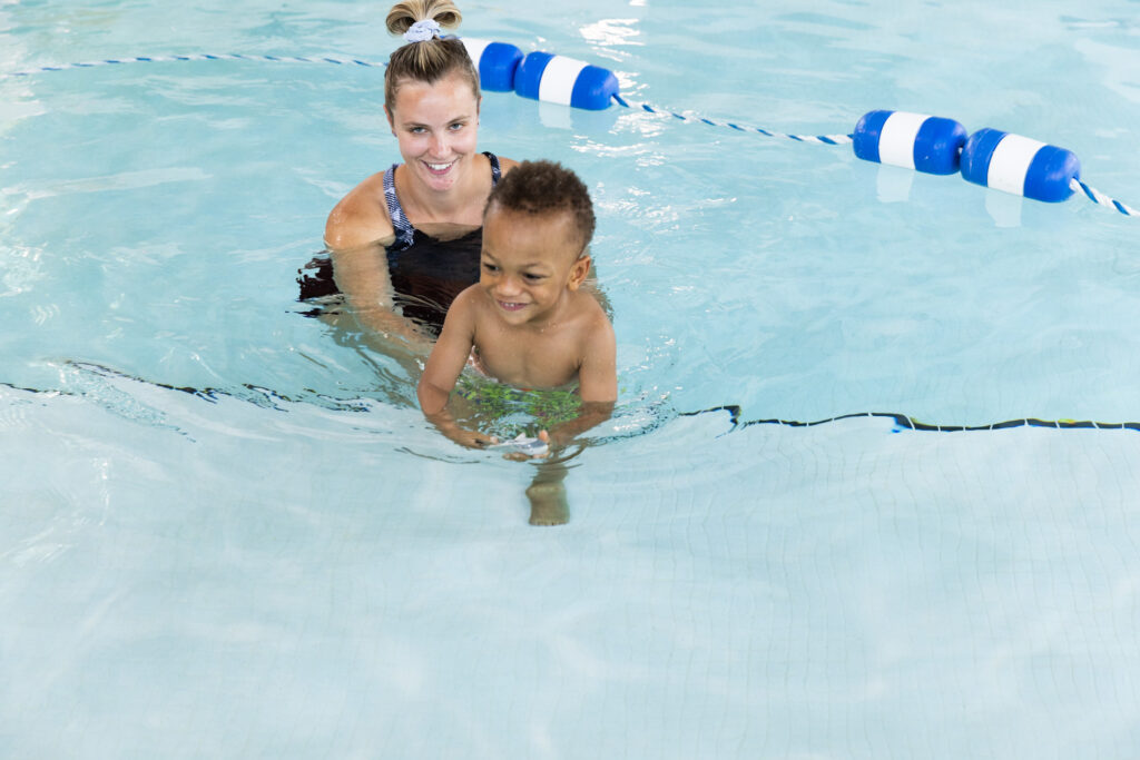 Therapist with little boy in pool smiling
