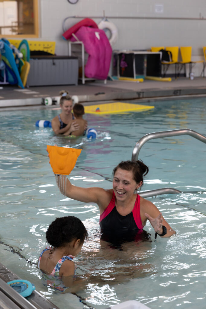 Children swimming in a pool with therapists.