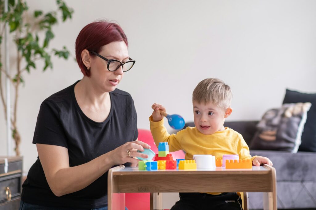 cheerful boy living with down syndrome play games in physical therapy rehabilitation room